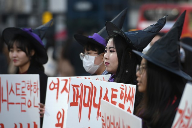 Mulheres sul-coreanas vestidas de bruxa seguram cartazes apoiando o feminismo durante um protesto para marcar o Dia Internacional da Mulher em Seul - 08/03/2019