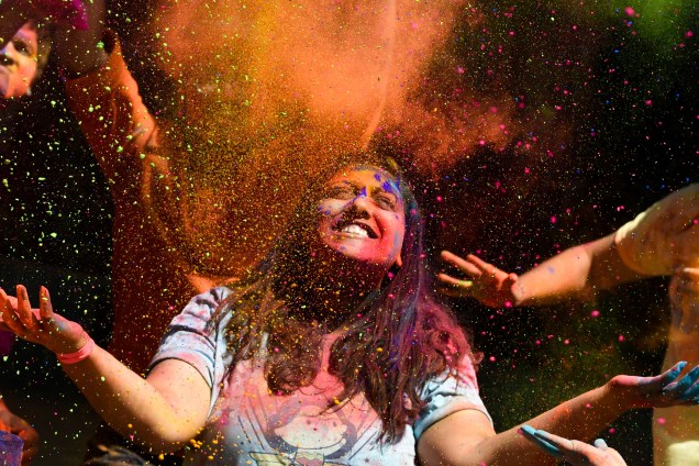 Foliões jogam pó colorido para o alto durante as celebrações do festival Holi, em Mumbai, na Índia - 21/03/2019