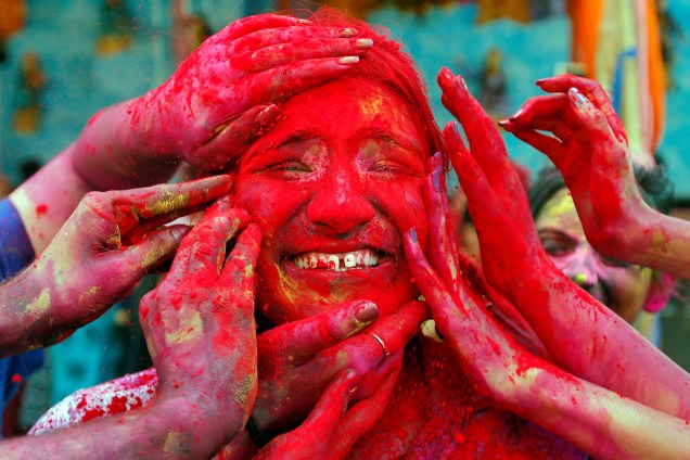 Uma mulher têm seu rosto colorido com um pó vermelho durante o festival Holi, em Calcutá, na Índia - 21/03/2019