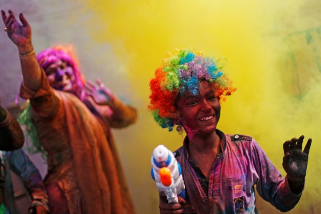 Foliões jogam pó colorido para o alto durante as celebrações do festival Holi, em Nova Deli, capital da Índia - 21/03/2019
