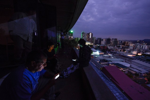Jornalistas usam seus smartphones, durante corte de energia em Caracas, na Venezuela - 07/03/2019