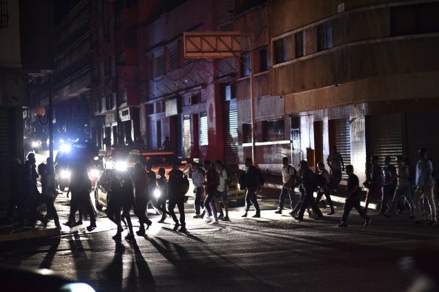 Pessoas atravessam uma rua durante um corte de energia em Caracas. O governo de Nicolás Maduro aponta "sabotagem" contra a principal represa de energia elétrica no país - 07/03/2019