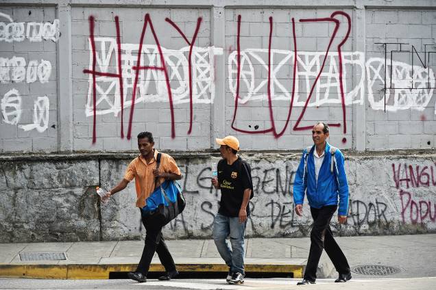 Pedestres caminham próximos de grafite com os dizeres 'Há luz?', durante novo apagão em Caracas, capital da Venezuela - 26/03/2019 Pedestres caminham próximos de grafite com os dizeres 'Há luz?', durante novo apagão em Caracas, capital da Venezuela - 26/03/2019