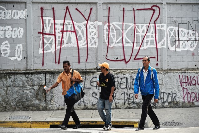 Pedestres caminham próximos de grafite com os dizeres 'Há luz?', durante novo apagão em Caracas, capital da Venezuela - 26/03/2019