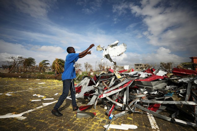 Homem empilha pedaços de metal arrancados de edifícios após a passagem do ciclone Idai na cidade de Beira, em Moçambique - 23/03/2019