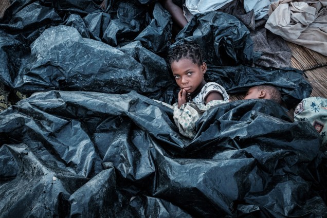 Enia Joaquin Luis, 11, acorda ao lado de sua irmã Luisa, 6, sob lençóis de plástico, para se proteger da chuva, em Beira Moçambique - 23/03/2019