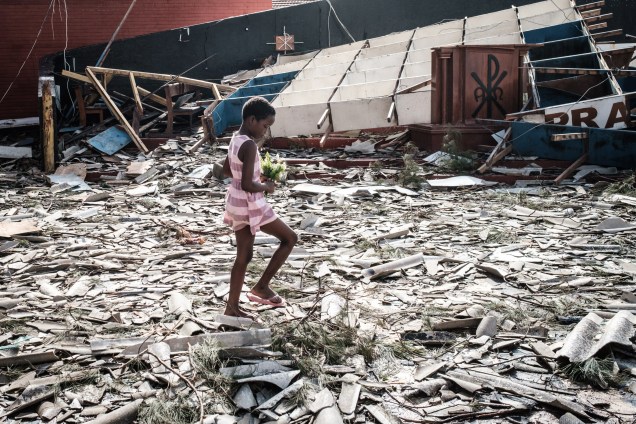Menina recolhe flores artificiais dos escombros de um edifício destruído pelo ciclone Idai na Igreja Católica do Sagrado Coração, em Beira, Moçambique - 24/03/2019