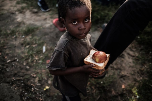 Garoto recebe alimentos em um centro de distribuição de um supermercado em Dondo, cerca de 35 km ao norte de Beira, cidade que ficou destruída após passagem do ciclone Idai em Moçambique - 27/03/2019