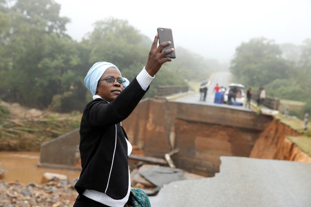Mulher tira selfie junto de destroços de ponte que atravessa o rio Umvumvu em Chimanimani, Zimbábue - 18/03/2019