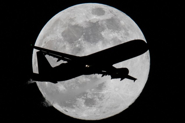 Avião é fotografado com a lua cheia ao fundo enquanto se prepara  para pousar no aeroporto de Frankfurt am Main, na Alemanha - 20/03/2019