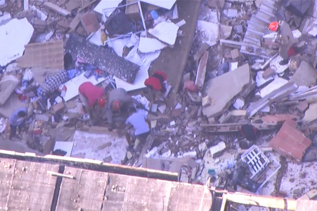 Bombeiros e voluntários procuram por vítimas em meio aos escombros de dois prédios que desabaram na comunidade Muzema, no Rio de Janeiro - 12/04/2019