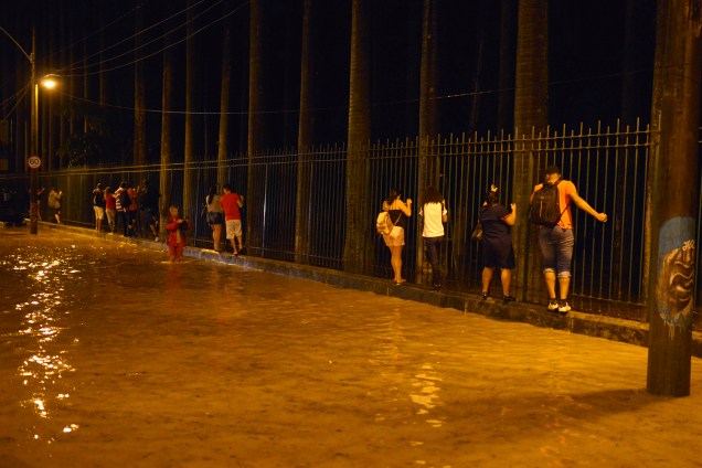 Moradores se agarram a uma grade para escapar da enchente causada pela forte chuva, no Jardim Botânico, Rio de Janeiro - 09/04/2019