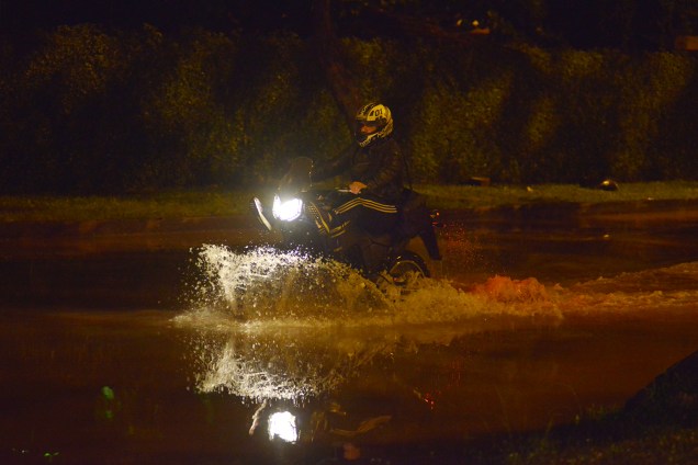 Um motociclista passa por uma rua alagada durante forte chuva no Jardim Botânico, zona sul do Rio de Janeiro - 09/04/2019