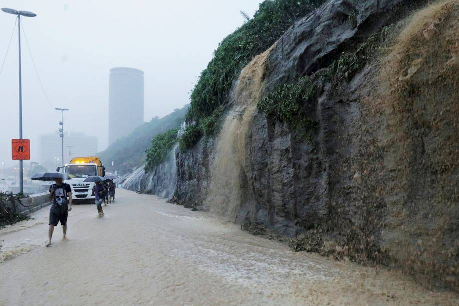 Pedestres caminham pela Avenida Niemeyer, durante uma chuva que deixou ao menos 3 mortos e um desaparecido - 09/04/2019