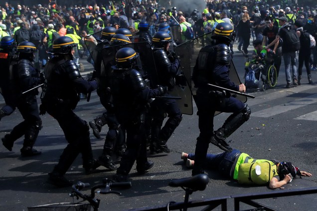 Um policial passa por cima de um manifestante durante a 23° manifestação consecutiva do movimentos dos Coletes Amarelos em Paris - 20/04/2019