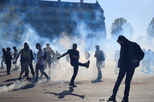 Manifestante chuta uma bomba de gás lacrimogênio disparada pela polícia durante o 23° protesto consecutivo aos sábados em Paris, na França - 20/04/2019