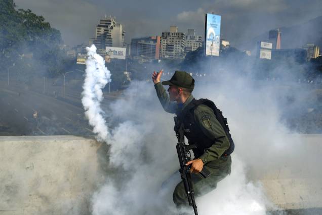 Membro da Guarda Nacional Bolivariana apoiador do líder de oposição Juan Guaidó lança uma bomba de gás lacrimogêneo durante confronto com forças leais ao governo do presidente Nicolas Maduro em frente à base militar de La Carlota em Caracas - 30/04/2019