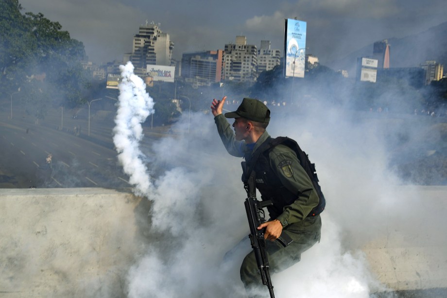 Membro da Guarda Nacional Bolivariana apoiador do líder de oposição Juan Guaidó lança uma bomba de gás lacrimogêneo durante confronto com forças leais ao governo do presidente Nicolas Maduro em frente à base militar de La Carlota em Caracas - 30/04/2019