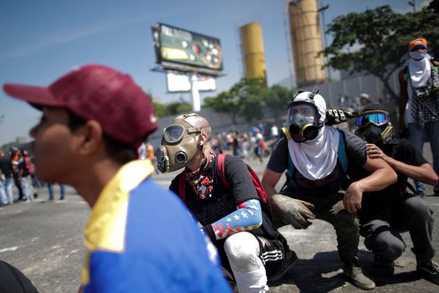 Manifestantes de oposição usam máscaras de gás para se proteger dos ataques das forças leais a Nicolás Maduro durante confrontos nos arredores da base aérea La Carlota em Caracas, na Venezuela - 30/04/2019