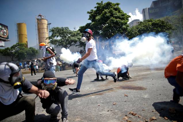 Manifestantes de oposição se protegem de gás lacrimogêneo em uma rua perto da Base Aérea Generalíssimo Francisco de Miranda La Carlota em Caracas durante confronto com forças leais ao presidente Nicolás Maduro - 30/04/2019 Manifestantes de oposição se protegem de gás lacrimogêneo em uma rua perto da Base Aérea Generalíssimo Francisco de Miranda La Carlota em Caracas durante confronto com forças leais ao presidente Nicolás Maduro - 30/04/2019