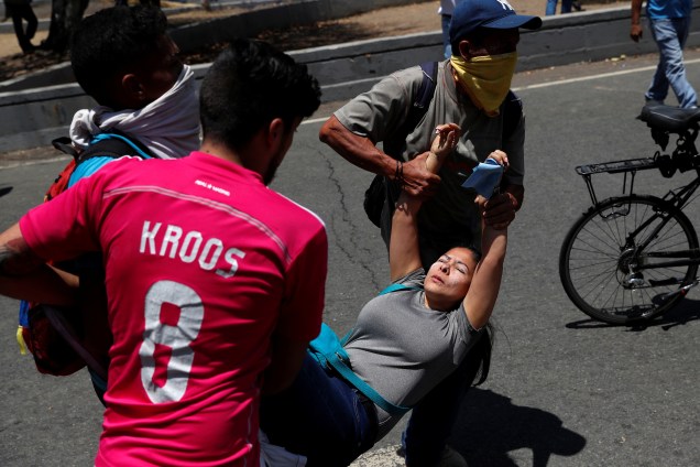 Manifestantes carregam uma mulher ferida durante confrontos com forças leais a Nicolás Maduro nos arredores da base aérea de La Carlota em Caracas, na Venezuela - 30/04/2019