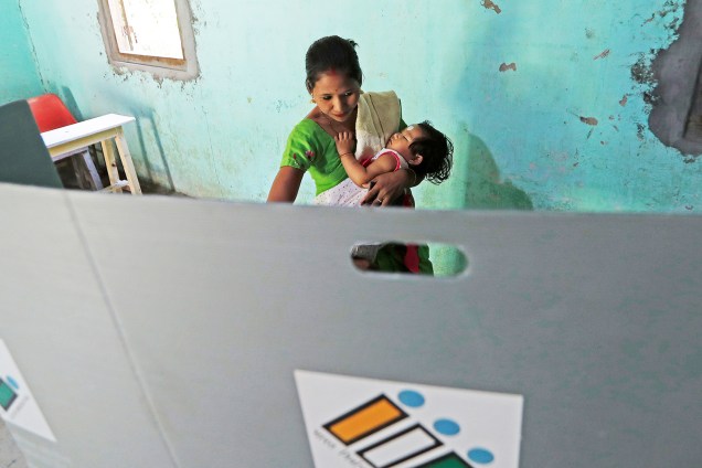 Mulher segura sua filha enquanto vota durante a primeira fase das eleições gerais em Majuli,na Índia - 11/04/2019