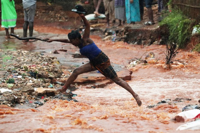 Mulher salta sobre inundação após o ciclone Kenneth atingir a cidade de Pemba, em Moçambique - 28/04/2019