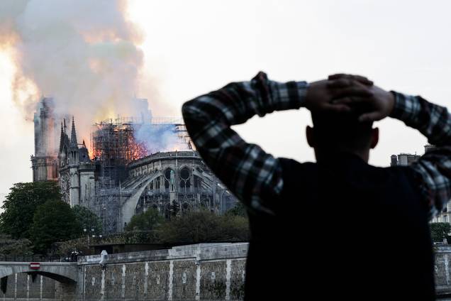 Homem observa incêndio atingir o topo da Catedral de Notre-Dame, localizada na região central de Paris, França - 15/04/2019