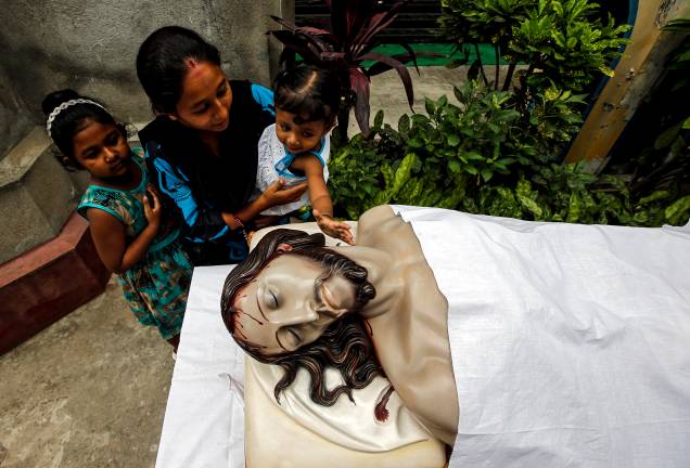Mulher ajuda a filha a tocar uma imagem de Jesus Cristo depois de participar de uma oração da Sexta-Feira Santa em Calcutá, Índia - 19/04/2019 Mulher ajuda a filha a tocar uma imagem de Jesus Cristo depois de participar de uma oração da Sexta-Feira Santa em Calcutá, Índia - 19/04/2019