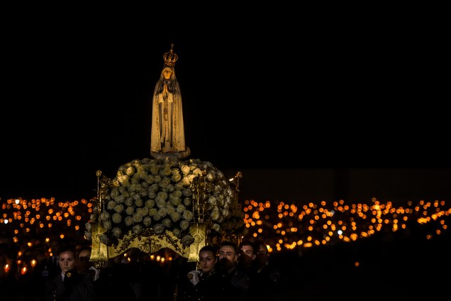Imagem de Nossa Senhora de Fátima é rodeada por fiéis carregando velas durante vigília em celebração ao 102º aniversário do aparecimento da Virgem Maria aos três pastorinhos em Portugal