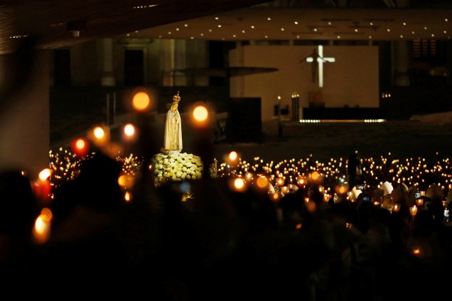Imagem de Nossa Senhora de Fátima é rodeada por fiéis carregando velas durante vigília em celebração ao 102º aniversário do aparecimento da Virgem Maria aos três pastorinhos em Portugal