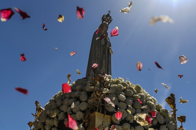 Católicos jogam pétalas de rosas em direção à imagem de Nossa Senhora de Fátima durante procissão no santuário dedicado à padroeira