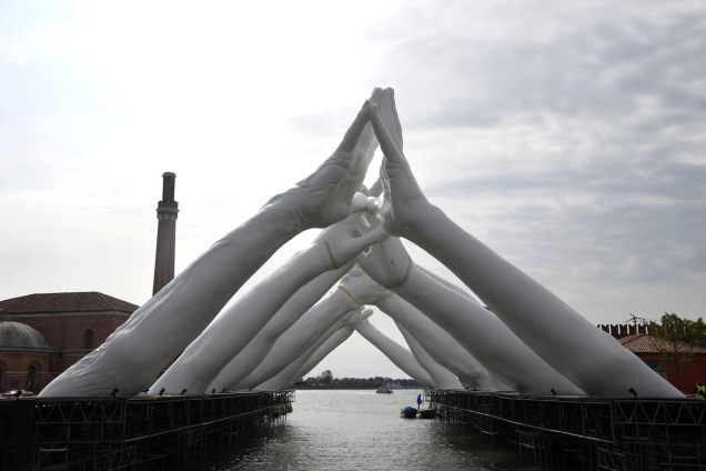 Instalação do artista italiano Lorenzo Quinn, intitulada  "Building Bridges" mostra seis pares de braços sobre rio veneziano, durante a 58ª Bienal Internacional de Arte de Veneza, na Itália. A exposição tem como tema “May You Live in Interesting Times”