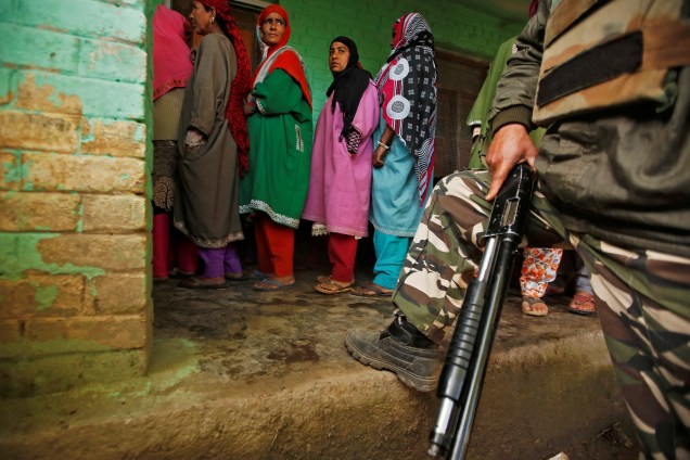 Mulheres aguardam em fila para votar enquanto guarda realiza patrulha em local de votação em Kund, no sul da Caxemira - 29/04/2019