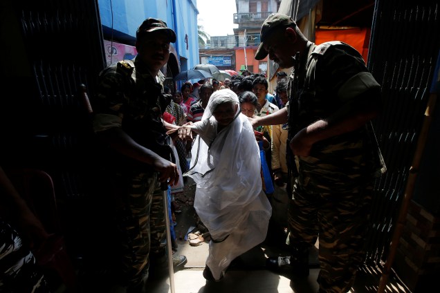 Seguranças auxiliam mulher a entrar em local de votação durante a quinta fase das eleições gerais em Howrah, cidade localizada nos arredores de Calcutá, Índia - 06/05/2019