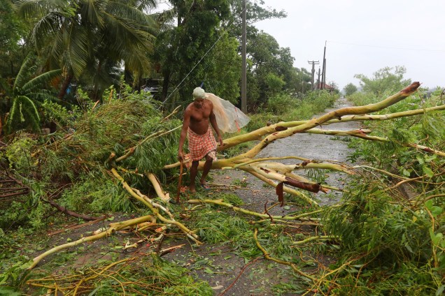 Homem corta ramos de uma árvore arrancada após passagem do ciclone Fani no distrito de Khordha, no estado de Odisha, leste da Índia - 03/05/2019