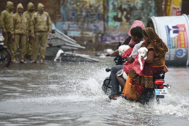 Mulheres carregam cães em motocicleta, durante enchente causada pela passagem do ciclone Fani na cidade de Puri, localizada no estado indiano de Odisha - 03/05/2019