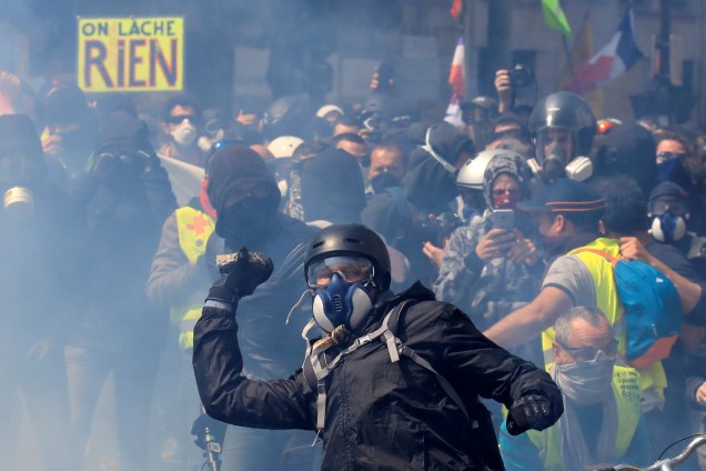 Manifestante com máscara de gás atira pedra contra policiais durante protesto realizado no Dia do Trabalho, em Paris, capital da França - 01/05/2019