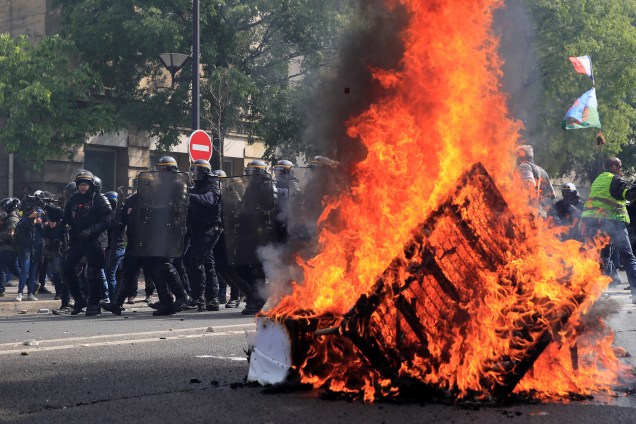 Policiais caminham próximos de barricada feita por manifestantes durante protesto realizado no Dia do Trabalho, em Paris, capital da França - 01/05/2019