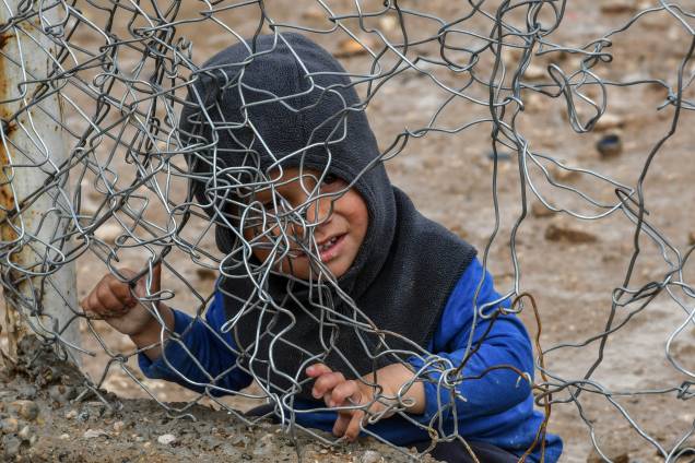 Menino brinca com cerca de arame que fecha o acampamento Al-Hol