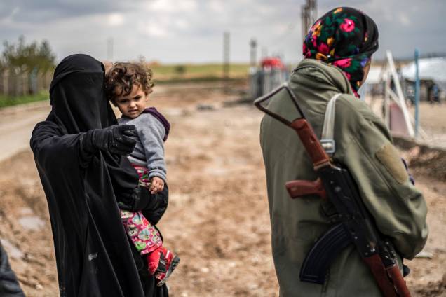 Mulheres andam armadas dentro do acampamento sírio