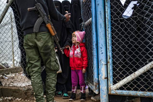 Menina olha para membro das Forças Democráticas da Síria (SDF) no campo de al-Hol, que abriga parentes de membros do grupo Estado Islâmico (IS), na província de al-Hasakeh, nordeste da Síria - 28/03/2019