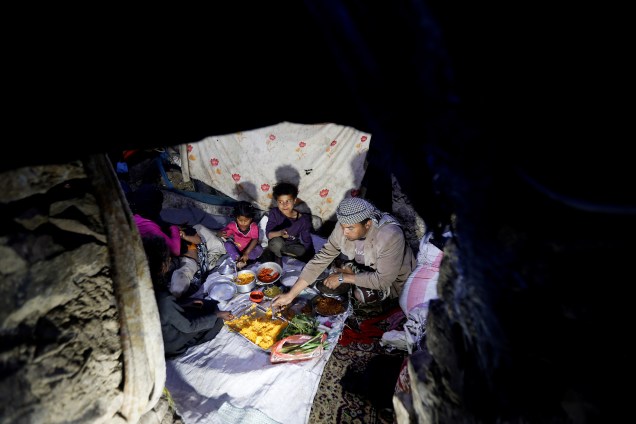 Homem faz refeição com sua família em cabana durante o mês sagrado do Ramadã, em uma favela nos arredores de Sanaa, no Iêmen - 07/05/2019