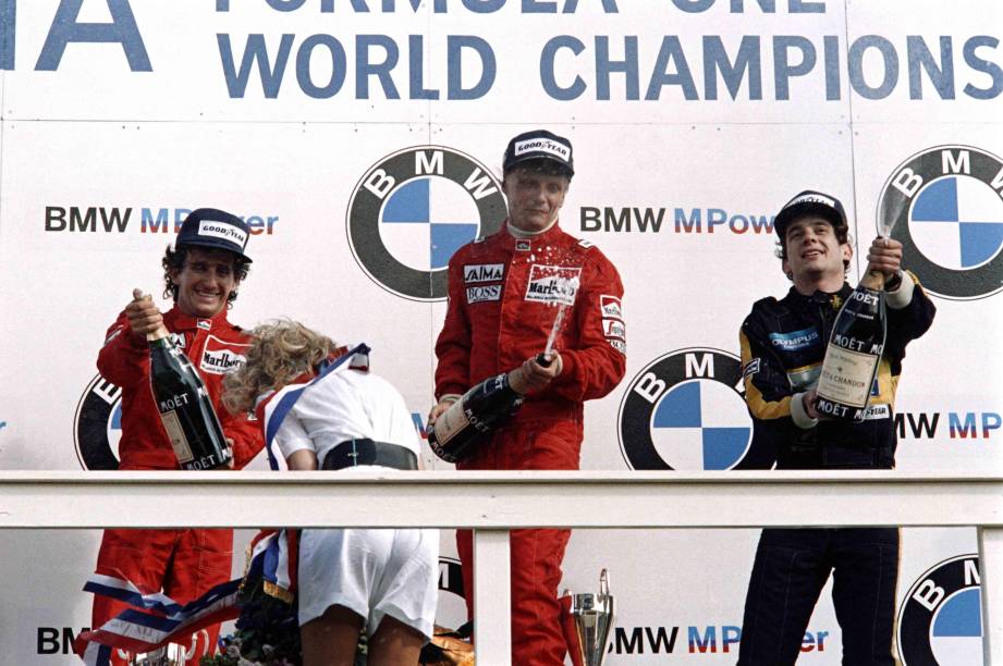 NikI Lauda, da McLaren, comemora a vitória no Grande Prêmio da Holanda de 1985, no pódio com o francês Alain Prost, também da McLaren, e o brasileiro Ayrton Senna, da Lotus