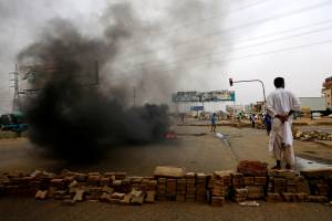 A Sudanese protester stands near a barricade on a street, demanding that the country’s Transitional Military Council handover power to civilians, in Khartoum