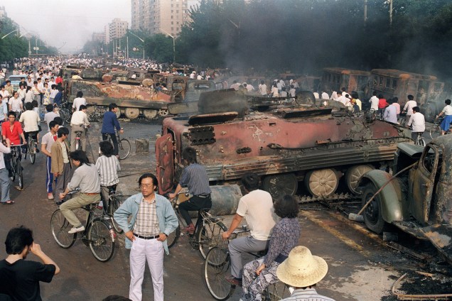 Chineses se reúnem perto dos restos mortais de mais de 20 veículos blindados queimados por manifestantes durante confrontos com soldados perto da Praça Tiananmen, em Pequim - 04/06/1989