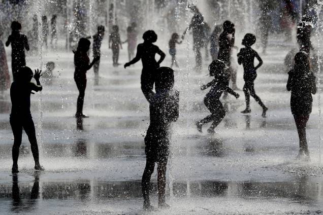 Crianças brincam debaixo de jatos d'água em fonte enquanto se refrescam durante forte onda de calor na cidade de Nice, localizada na França - 26/06/2019 Crianças brincam debaixo de jatos d'água em fonte enquanto se refrescam durante forte onda de calor na cidade de Nice, localizada na França - 26/06/2019