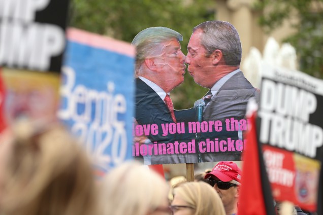 Manifestantes exibem um cartaz com o presidente dos Estados Unidos, Donald Trump, e o líder do partido Brexit, Nigel Farage, durante manifestação contra a visita de Trump em Londres - 04/06/2019