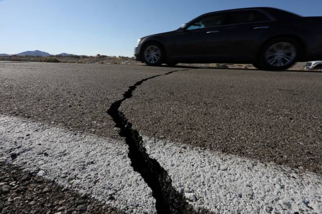 A car passes over a fissure that opened on a highway during a powerful earthquake that struck Southern California, near the city of Ridgecrest