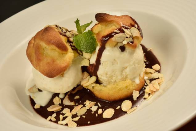 Profiteroles com sorvete de baunilha e calda de chocolate meio amargo: uma das variedades de sobremesa Profiteroles com sorvete de baunilha e calda de chocolate meio amargo: uma das variedades de sobremesa